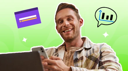 An eCommerce owner smiling at a phone beside a laptop